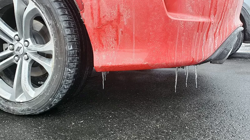 Car fender with icicles in cold weather